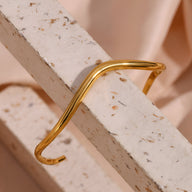 Bracelet jonc en acier inoxydable doré à finition ondulée, style moderne et épuré.