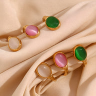 Bracelet jonc en acier doré avec pierres naturelles ovales jade, agate rose et cristal blanc sur tissu beige.