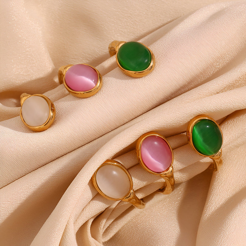 Bracelet jonc en acier doré avec pierres naturelles ovales jade, agate rose et cristal blanc sur tissu beige.