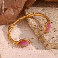 Bracelet jonc doré en acier inoxydable avec perles naturelles roses ovale serties aux extrémités.