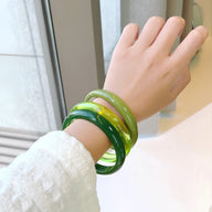 Lot de trois bracelets joncs en résine verts et jaune lumineux, finition lisse brillante, style moderne féminin.