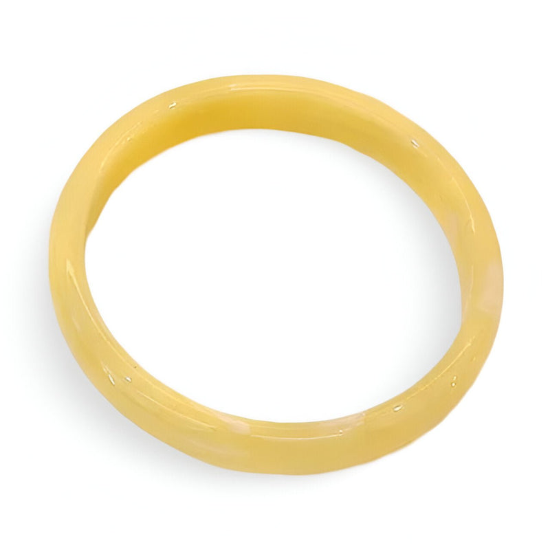 Bracelet jonc en résine jaune pâle à finition lisse et brillante.