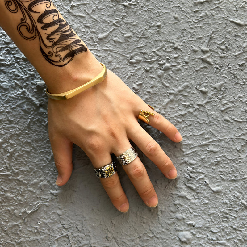 Bracelet jonc en titane doré, finition lisse et minimaliste, porté au poignet masculin.