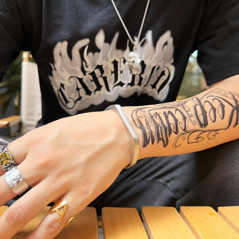 Bracelet jonc en titane argenté au design épuré porté au poignet, style masculin moderne.