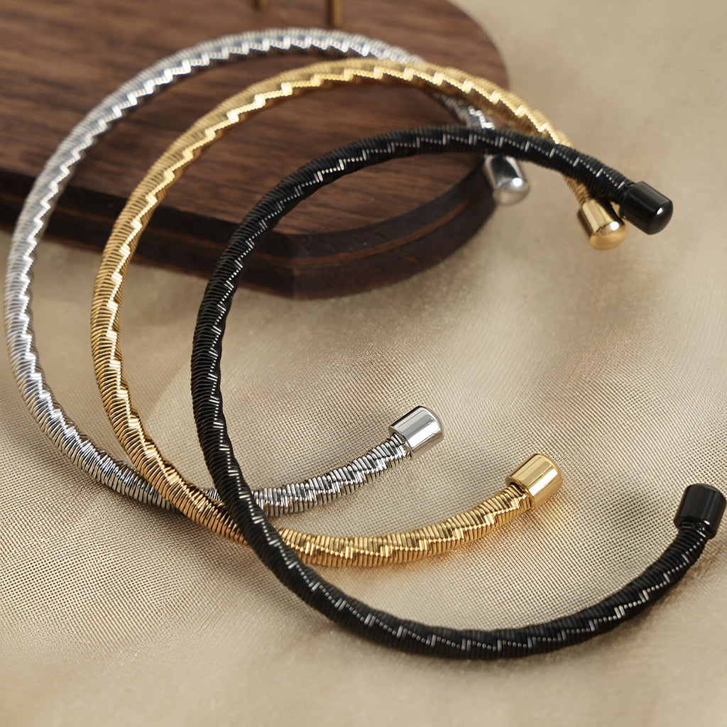 Bracelets jonc en titane plaqué or, argent et noir, design texturé et ouvert.