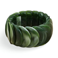 Bracelet jonc épais en acrylique vert marbré avec design ondulé féminin.