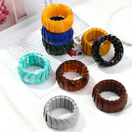 Bracelets joncs épais en acrylique aux textures torsadées, coloris variés comme orange, bleu, noir, marron et gris.