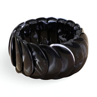 Bracelet jonc épais noir en acrylique avec design sculpté ondulé pour femme.