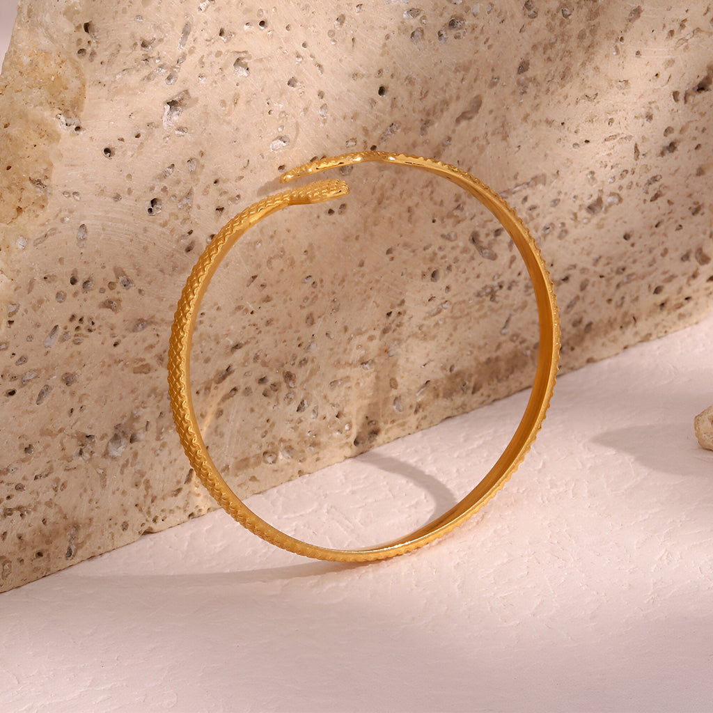 Bracelet jonc doré en acier inoxydable avec texture serpent élégante et finition lisse.