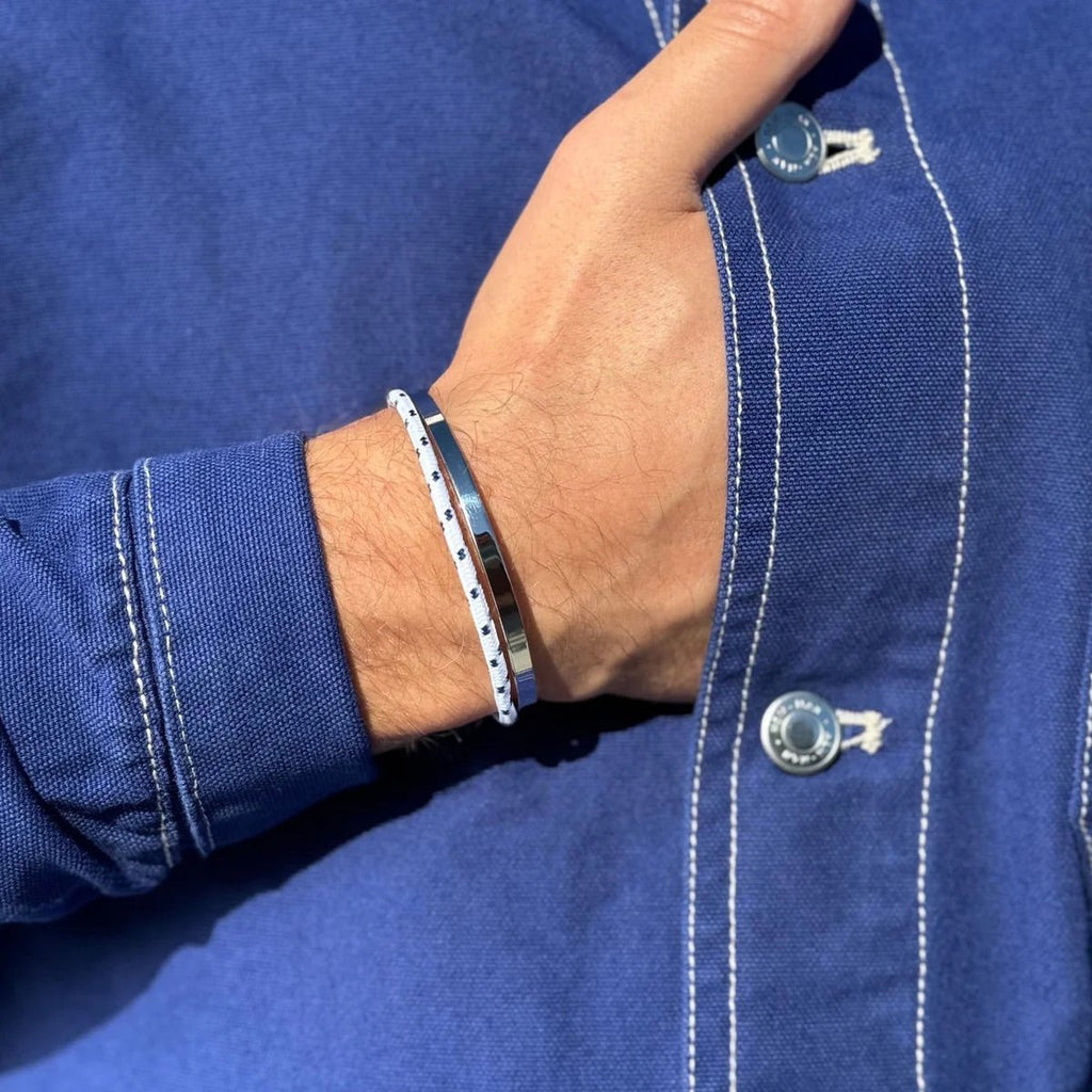Bracelet jonc en acier inoxydable argenté avec cordon noir porté sur un poignet masculin, style minimaliste.