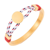 Bracelet jonc doré avec cordon bleu marine et blanc tressé, médaillon rond central lisse.