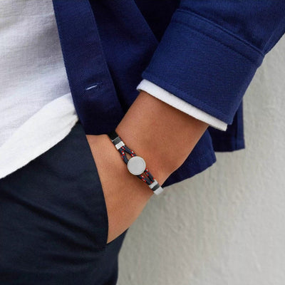 Bracelet jonc argent avec cordon bleu marine et médaillon rond porté au poignet.
