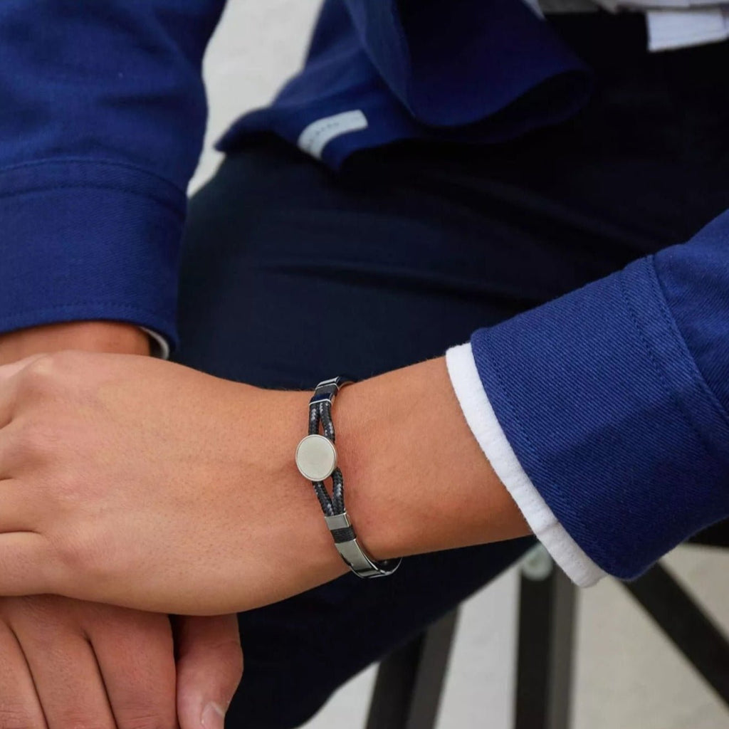 Bracelet jonc argent avec cordon noir et médaillon central rond porté sur poignet homme.