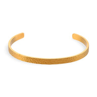 Bracelet jonc fin en acier inoxydable doré avec finition martelée, design épuré et élégant.