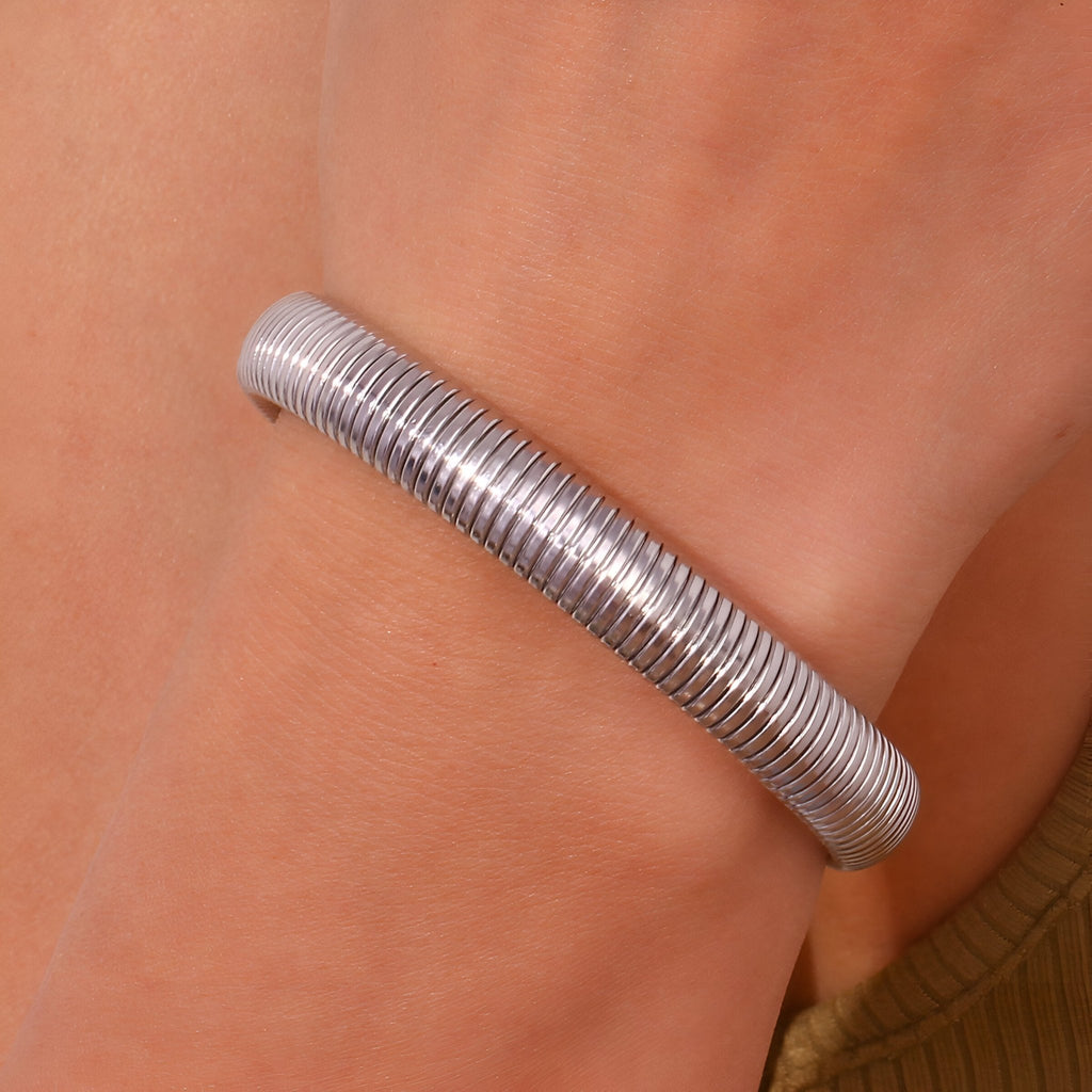 Bracelet jonc flexible en maille d'acier inoxydable argenté élégant porté au poignet.