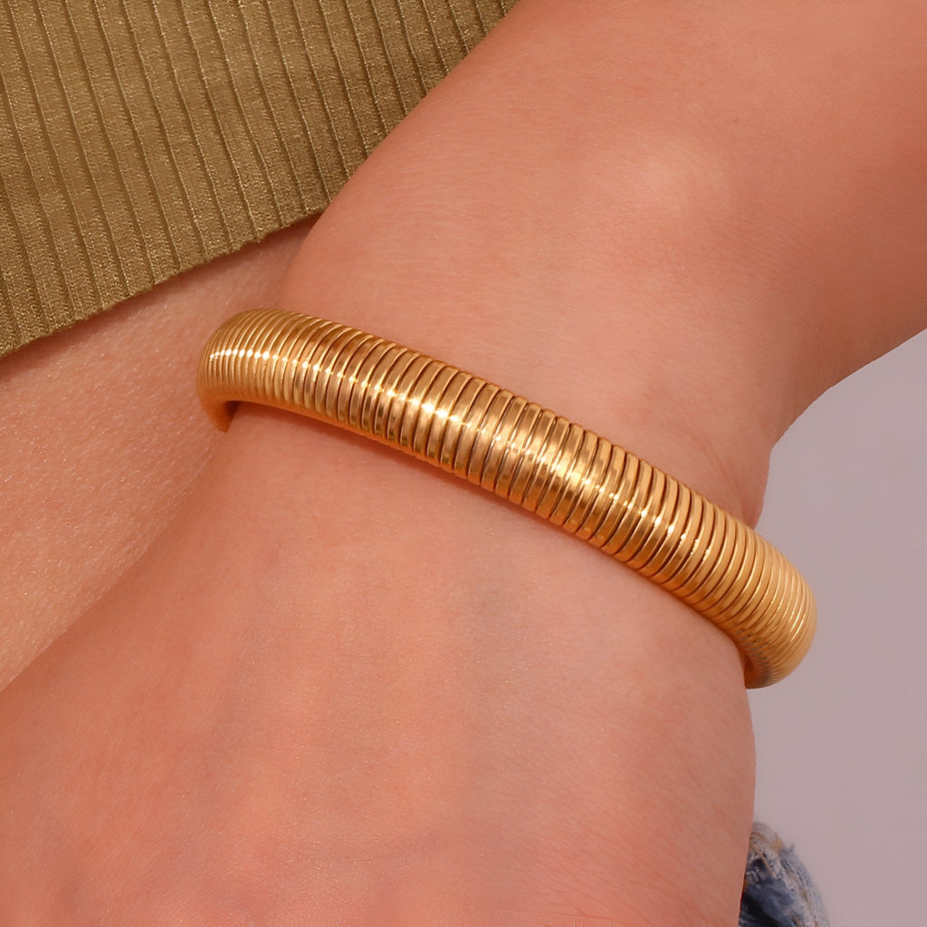 Bracelet jonc flexible en maille d'acier inoxydable doré, finition lisse et brillante.