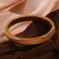 Bracelet jonc flexible en acier inoxydable doré, maille serpent élégante et lisse.