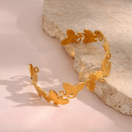 Bracelet jonc en acier inoxydable doré avec motifs floraux délicats découpés.