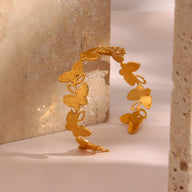 Bracelet jonc en acier inoxydable doré avec motifs floraux délicats et finition texturée.