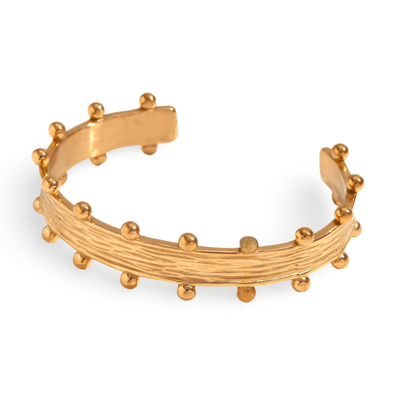 Bracelet jonc plaqué or 18 carats avec texture rayée et billes sphériques décoratives.