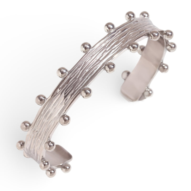 Bracelet jonc en acier inoxydable argenté avec texture striée et petites sphères décoratives.