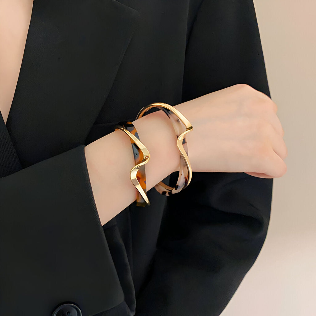 Bracelet jonc en métal doré et acrylique à motif léopard porté sur poignet féminin, modèle Valencia.