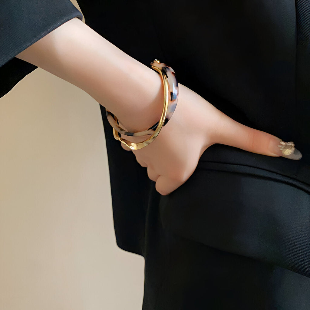 Bracelet jonc léopard en acrylique avec détails métal doré porté sur poignet femme.