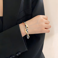 Bracelet jonc en acrylique léopard beige et métal doré élégant, porté au poignet féminin.