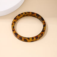 Bracelet jonc en acrylique marron avec motif léopard brillant et finition lisse.