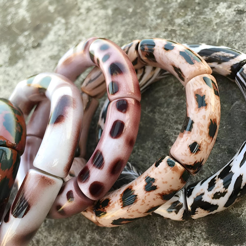 Lot de bracelets joncs en acrylique avec motif léopard dans des tons beige, marron, rose et noir.