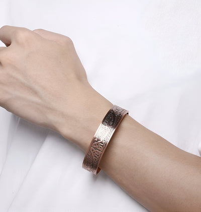 Bracelet jonc magnétique en cuivre bronze avec gravures décoratives porté au poignet homme.
