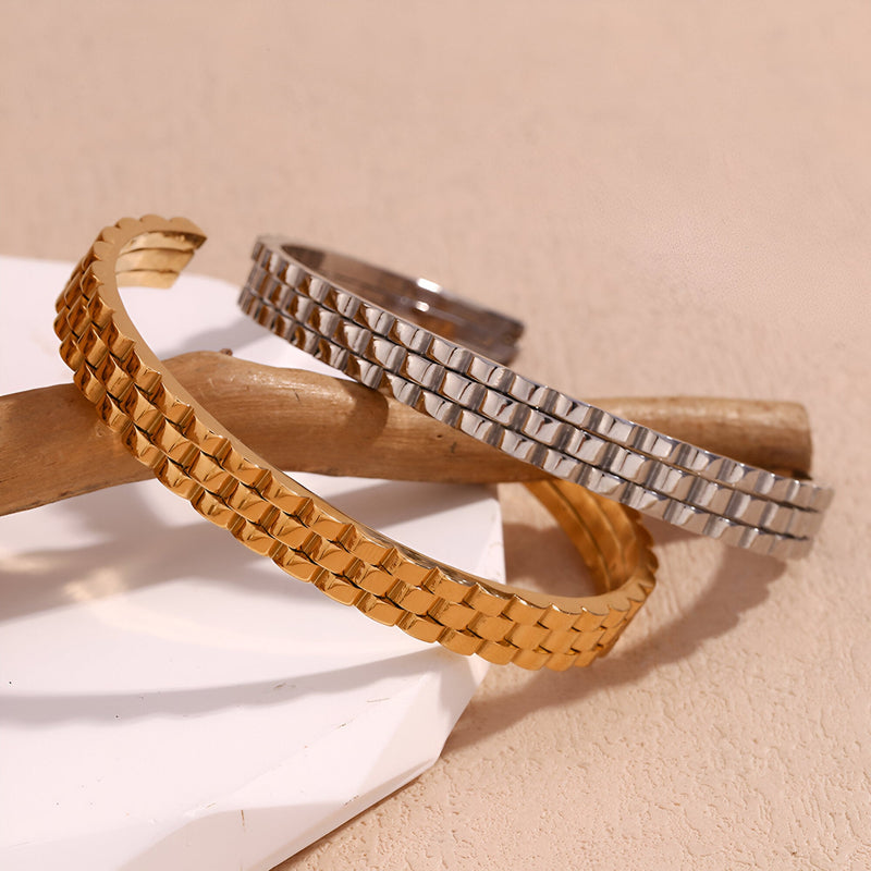Bracelet jonc maille gourmette en acier inoxydable couleur or doux et argent brillant sur fond beige.