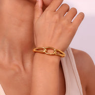 Bracelet jonc doré avec maillon central ovale en acier inoxydable, style minimaliste et élégant.