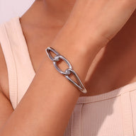 Bracelet jonc argenté en acier inoxydable avec maillon central large et épuré, style moderne.