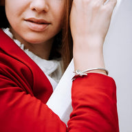 Bracelet jonc argenté en acier inoxydable avec nœud délicat porté sur poignet féminin.