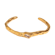 Bracelet jonc ondulé doré en acier inoxydable avec pierre rectangulaire claire centrale.