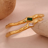 Bracelet jonc ondulé en acier inoxydable doré avec pierres rectangulaires verte et blanche.