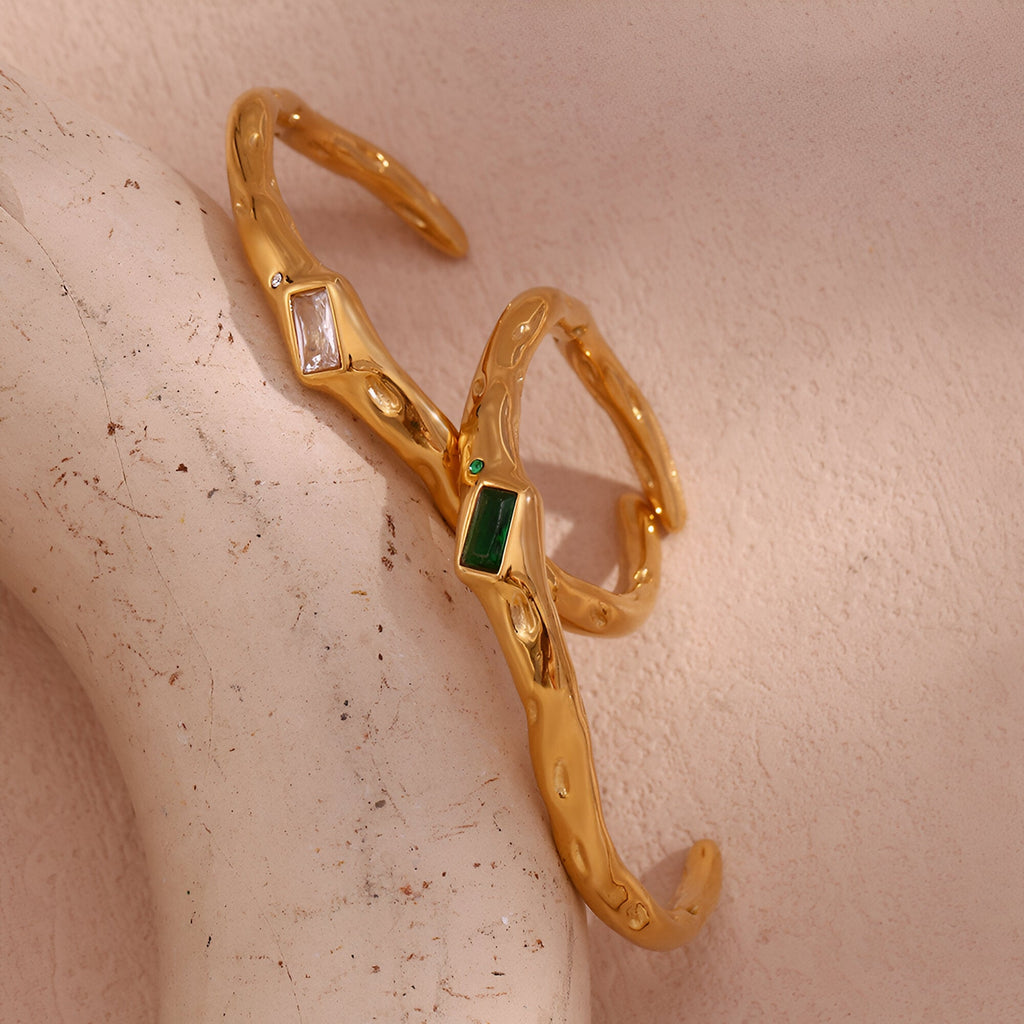 Bracelet jonc ondulé en acier doré avec pierres rectangulaires verte et blanche.