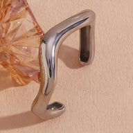 Bracelet jonc ondulé en acier inoxydable argenté, finition brillante, design moderne et minimaliste.