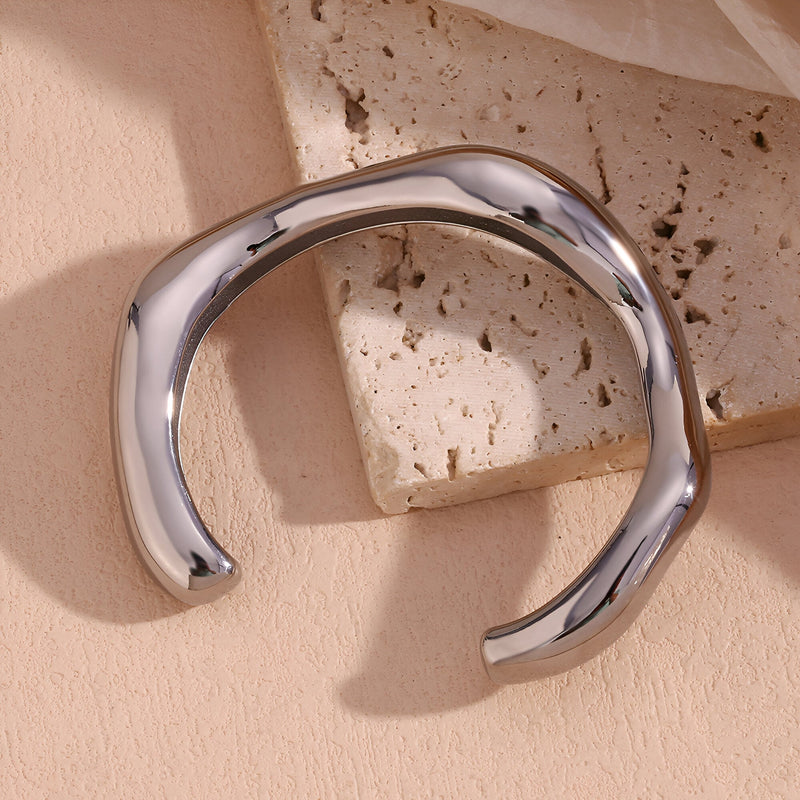 Bracelet jonc ondulé en acier inoxydable argenté au design moderne et lisse.