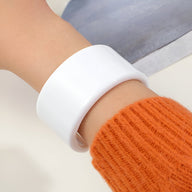 Bracelet jonc ouvert en résine blanc brillant porté sur le poignet, style moderne et épuré.