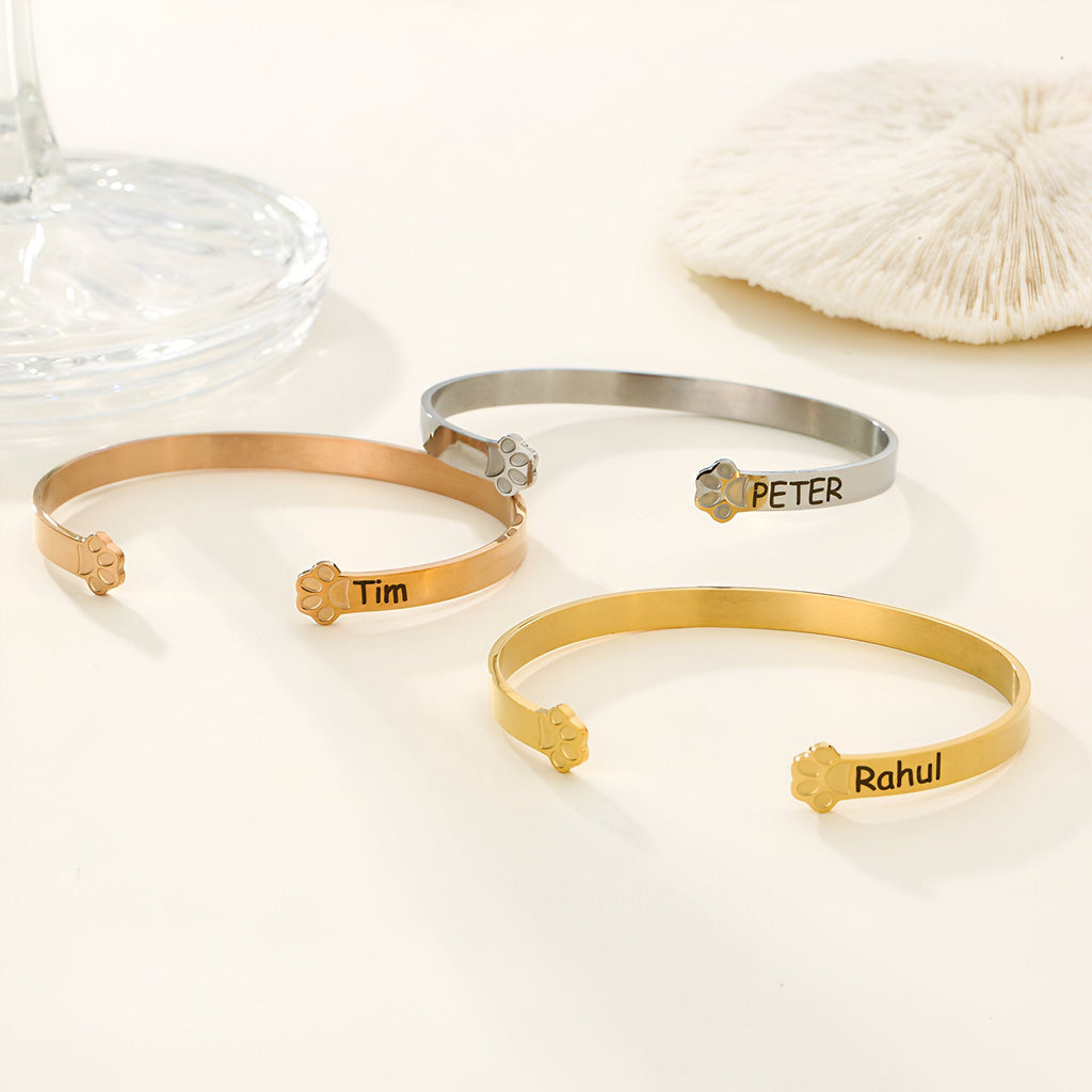 Trois bracelets joncs personnalisés en argent, or rosé et or jaune avec motifs patte d'animal gravée et prénoms Tim, Peter,.