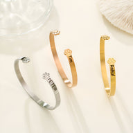 Trois bracelets joncs personnalisés en argent, or rosé et or avec patte d'animal gravée et noms différents.