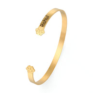 Bracelet jonc en or rosé avec gravure prénom et motif patte d'animal aux extrémités.