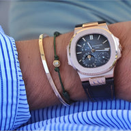 Bracelet jonc fin en acier inoxydable doré, finition brillante, porté au poignet avec montre à bracelet cuir noir et.