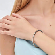 Bracelet jonc fin en acier inoxydable argenté porté au poignet, style minimaliste élégant.