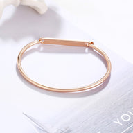 Bracelet jonc fin en acier inoxydable or rosé avec plaque personnalisable, style épuré.