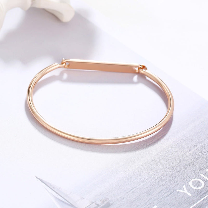 Bracelet jonc fin en acier inoxydable or rosé avec plaque personnalisable, style épuré.