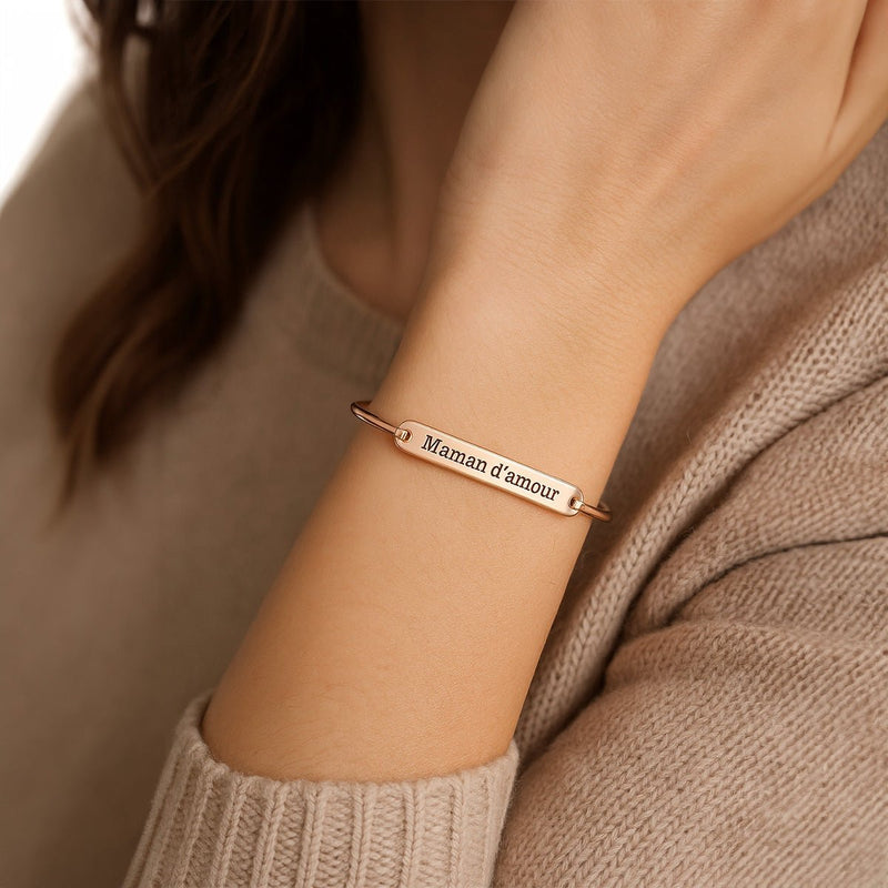 Bracelet jonc fin en acier inoxydable or rosé avec gravure personnalisée porté au poignet féminin.