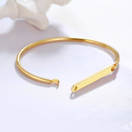 Bracelet jonc en acier inoxydable doré, design minimaliste avec extrémités ouvertes et plaque personnalisable.